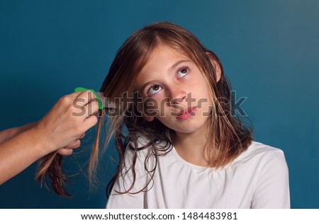 Sad little girl combing her hair with a lice comb