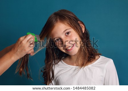 Happy little girl combing her hair with a lice comb