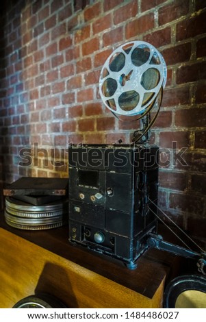 photo of an old movie projector on brick wall background. Old style movie projector, still-life.