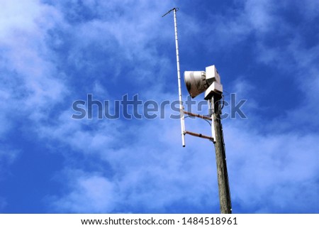 Emergency alert siren with blue sky and clouds Royalty-Free Stock Photo #1484518961