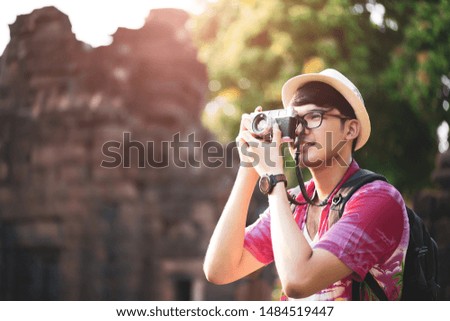 Young Man Photographer Traveler with backpack taking photo with his camera, Great wall in background at historical place. Lifestyle and travel concept.