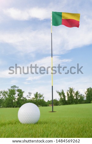 Benin flag on golf course putting green with a ball near the hole