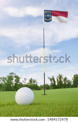 North Carolina flag on golf course putting green with a ball near the hole