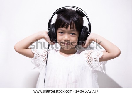Cute little girl Listening to music with fun headphones on a white background, Asian children