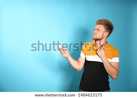 Young man with air conditioner remote on blue background. Space for text