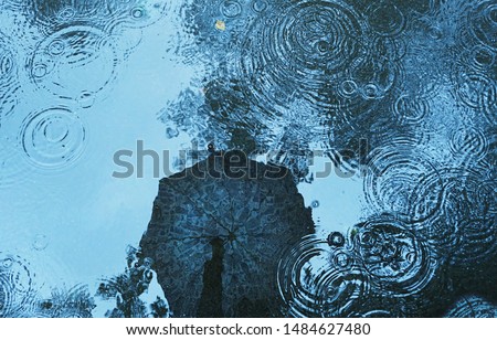 reflection umbrella in puddle, wet asphalt natural background. rainy weather season. flat lay. copy space Royalty-Free Stock Photo #1484627480