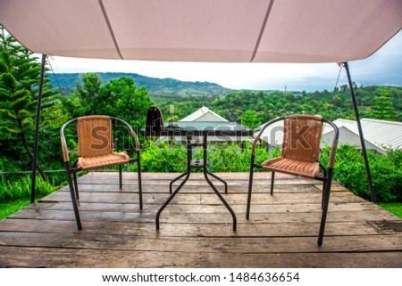 The background of the chair and counter to sit and watch the scenery, allowing tourists to stop and take public pictures while traveling, the atmosphere is surrounded by trees and mountains.