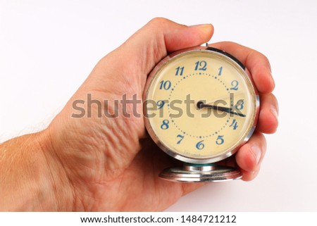 Alarm clock in human hand on a white background