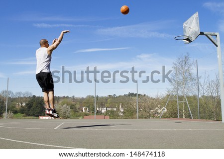 Portrait of a Basketball player taking a jump Shot on an outdoor basketball court Royalty-Free Stock Photo #148474118
