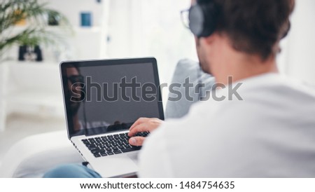 Man listening to music and using laptop in the living room.