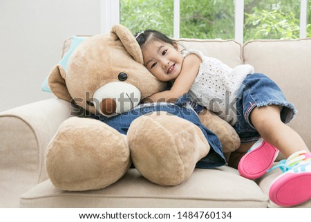 asian kid  play and hug teddy bear in living room