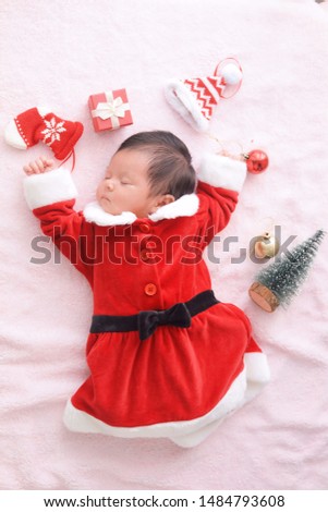 Portrait lovely newborn in red dress with gift box sleeping on mat,happy Christmas celebration time concept.
