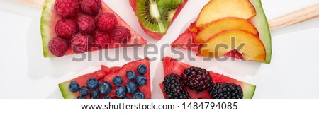 panoramic shot of delicious dessert with watermelon on sticks and berries on white background