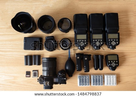 top view of work space photographer with digital camera, battery charger camera, memory card storage box, external harddisk, flash, computer laptop, and camera accessory on wooden background