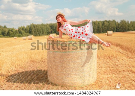 Woman in the autumn field landscape. Haystask rolls on agriculture field.