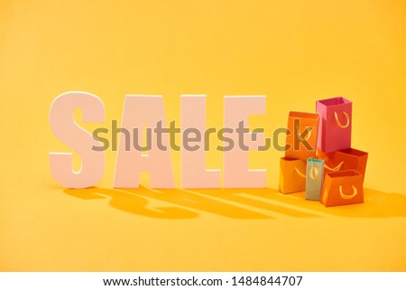 white sale lettering with shopping bags on bright orange background