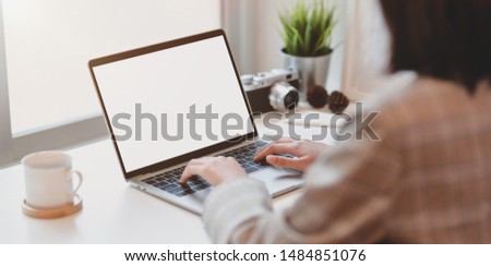 Young businesswoman typing on blank screen laptop computer in comfortable office 