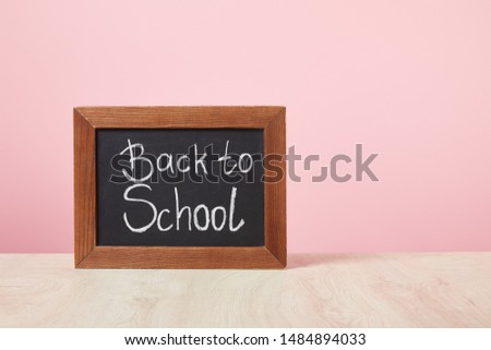 chalkboard with back to school lettering isolated on pink