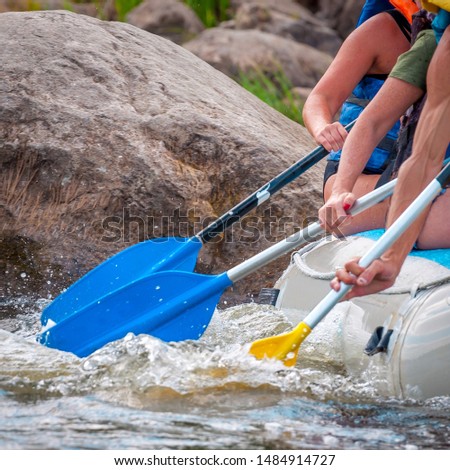Rafting trip. Close up view of oars with splashes of water. Rowers make an effort to overcome the turbulent river. The concept of teamwork, healthy lifestyle.