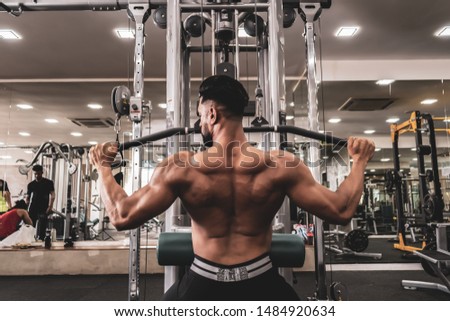 Fit man on lat pulldown machine at the health club. Work out on Pulldown Weight Machine Royalty-Free Stock Photo #1484920634