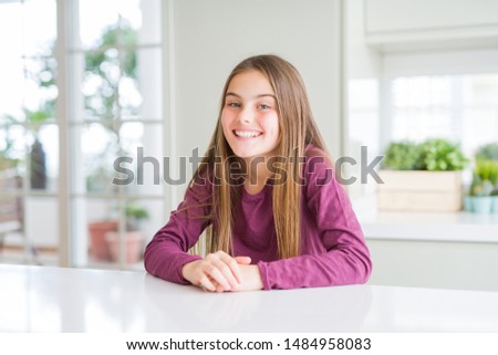 Beautiful young girl kid on white table with a happy and cool smile on face. Lucky person.