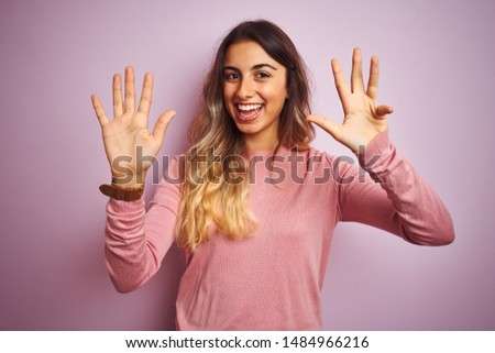 Young beautiful woman wearing a sweater over pink isolated background showing and pointing up with fingers number nine while smiling confident and happy.