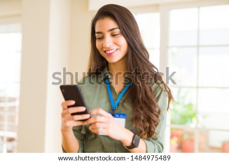 Beautiful young business woman wearing id card and working using smartphone