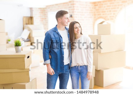 Beautiful young couple moving to a new house looking away to side with smile on face, natural expression. Laughing confident.