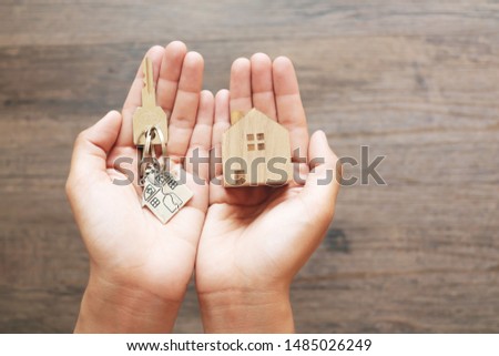 Close up of hands holding wood house model and home keys.building, mortgage, real estate and property concept.