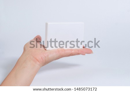 Female hand hold a white tablet, business card, box on a white background.