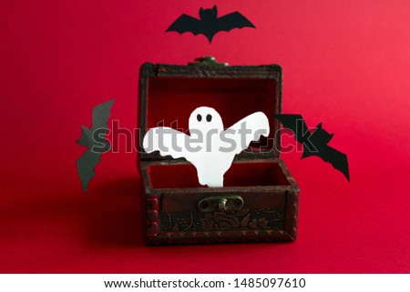 paper cut scary ghost and bats   fly out of an old vintage  wooden chest on a black background, festive Halloween card