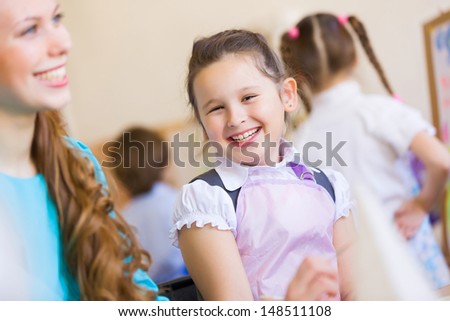 Little girl painting with teacher at kindergarten