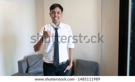 portrait of casual Asian business man standing with thumb up at his indoors living room
