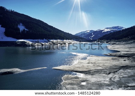 panoramic view of a reservoir lake at winter with cracked mud around. Water in the high alps in austria by day with beautiful light.