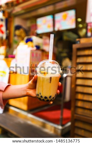Young girl take a photo of trendy drink ( named Tapioca milk tea )