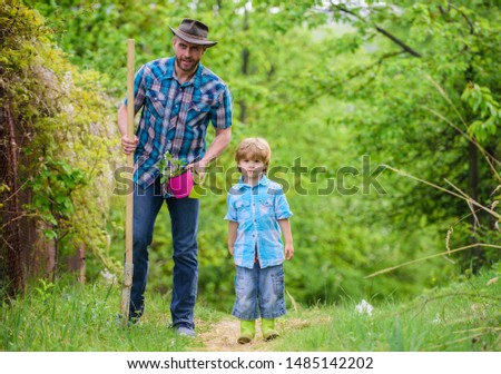 Planting flowers. Dad teaching little son care plants. Little helper in garden. Make planet greener. Growing plants. Take care of plants. Day of earth. Boy and father in nature. Gardening tools.