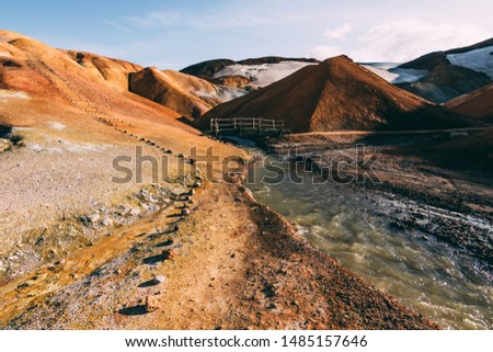 Kerlingarfjoll geothermal steaming yellow, orange colorful mountains hills, stairs, paths, people hiking, walking. Blue sky background, beautiful landscape Icelandic nature highlands Iceland, snow