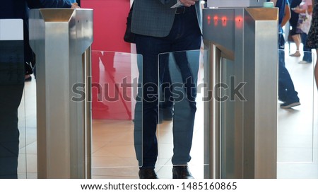 Man in grey suit jacket and blue jeans passing electronic turnstile with barcode scanner. Media. Access control for business center, close-up