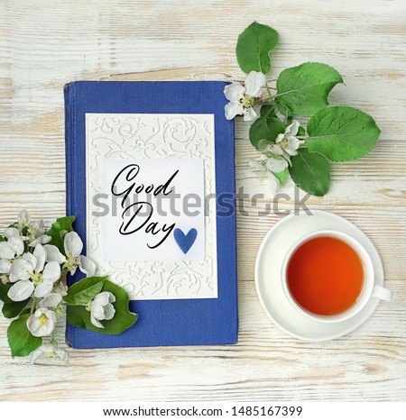 Good Day. tea cup, apple flowers, book and greeting card. elegant still life with spring flowers. breakfast, tea ceremony. flat lay