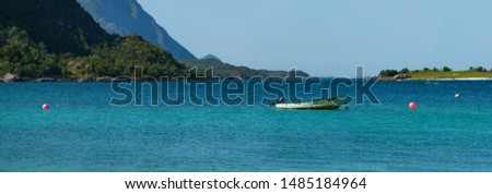 Picturesque Bay in Northern Norway of Turquoise colored ocean with high Mountains in the background - Wide panoramic picture of Norwegian landscape in summer.