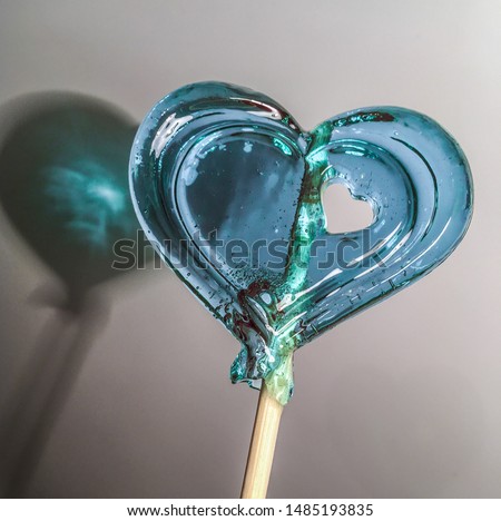 Lollipop in the form of a blue heart with a hole in the form of a heart
