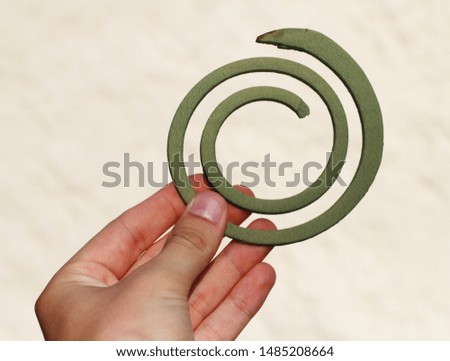 Hand holding green spiral mosquito repellent coil