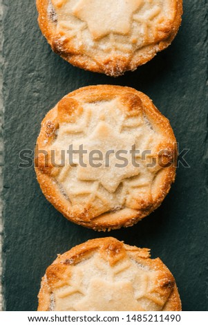 Delicious Christmas mince pies in a row. Snowflake dough ornament and sugar on them