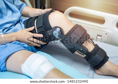 Asian woman patient with bandage compression knee brace support injury on the bed in nursing hospital.healthcare and medical support. Royalty-Free Stock Photo #1485232490