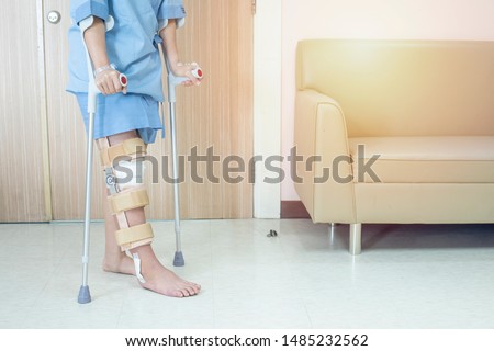 Patient try to walk with crutch in hospital ware knee brace support after do posterior cruciate ligament surgery ,Bandage on knee of asian woman on crutches.healthcare and medical concept. Royalty-Free Stock Photo #1485232562