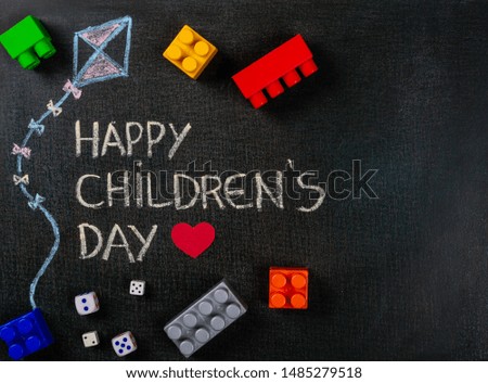 Blackboard written Happy Children's Day and kite drawing with scattered assembly pieces. Copy space.