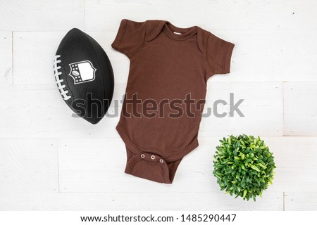 Blank brown baby bodysuit with football and plant on white background, newborn apparel football mockup