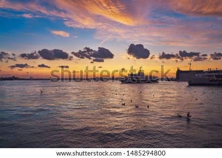 Beautiful sunset in Istanbul, Turkey. Silhouettes of Hagia Sophia and Blue Mosque, yellow/red sky with red/black clouds, seagulls and ferries (vapur) of Bosphorus. Landscape taken in July in summer. 