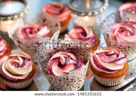A beautiful, colorful stock image with cupcakes on a cake stand with decorations of flowers and candles
