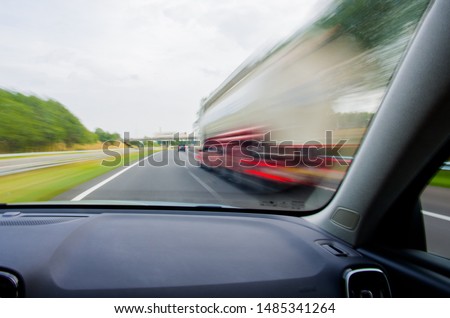 Car is going to overtake white / red truck on Dutch/European two-lane highway at high speed. Dashboard view with motion blur. Royalty-Free Stock Photo #1485341264